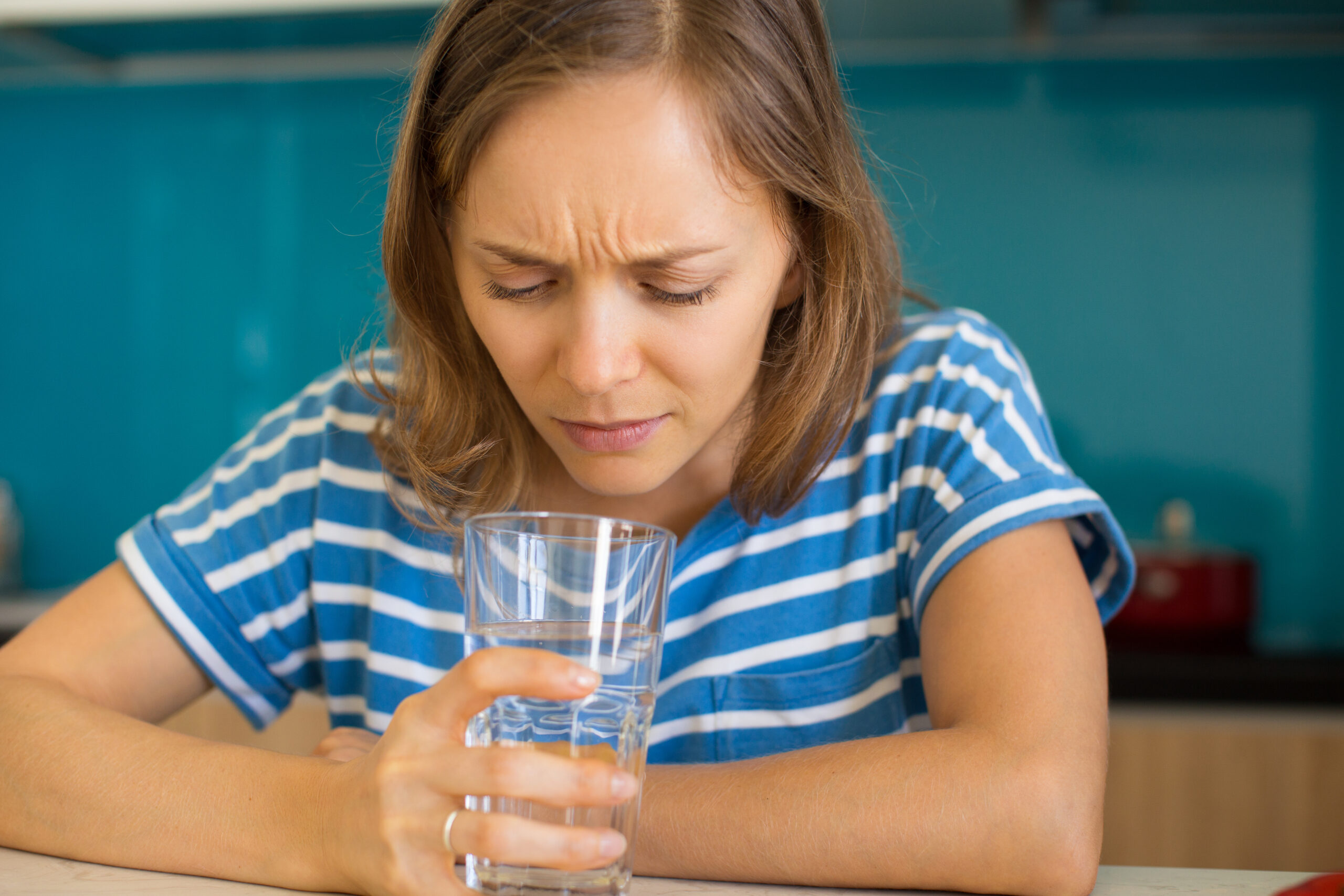 Dissatisfied Woman Looking into Glass of Water